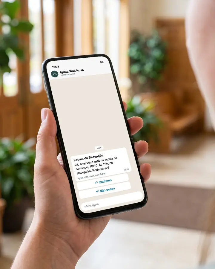 Uma mão segura um celular com a mensagem da escala no WhatsApp e os botões Confirmo e Não posso.