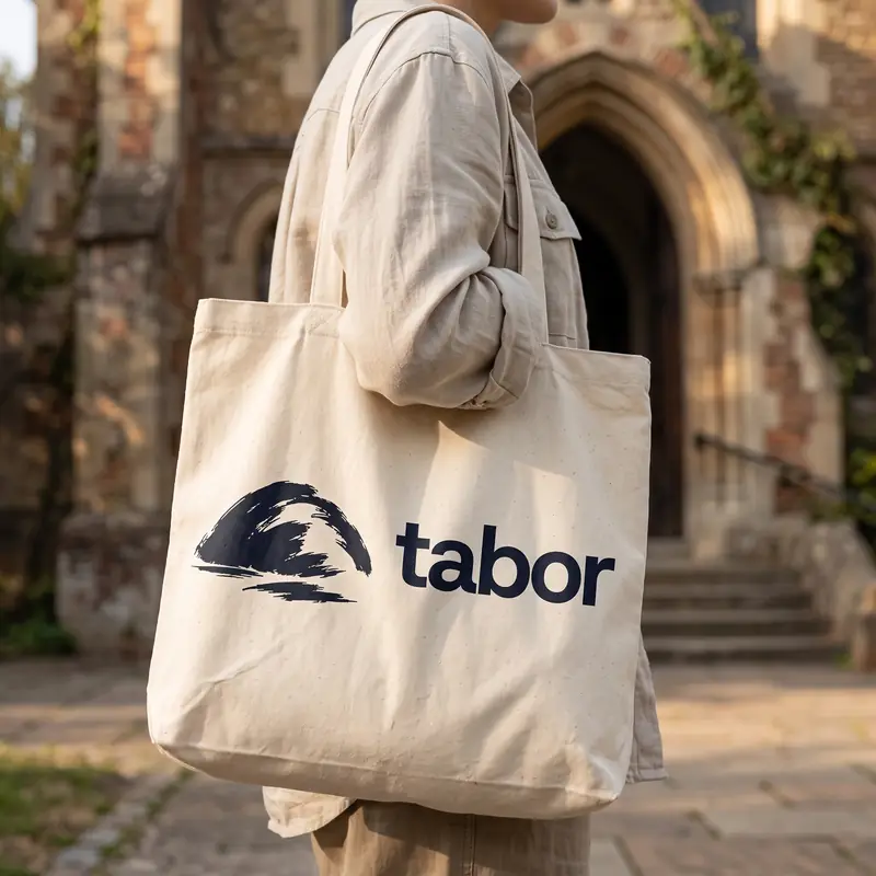 Uma pessoa de costas carrega uma sacola de pano com o nome Tabor.
